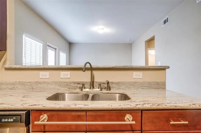 kitchen with light stone counters, dishwasher, and sink