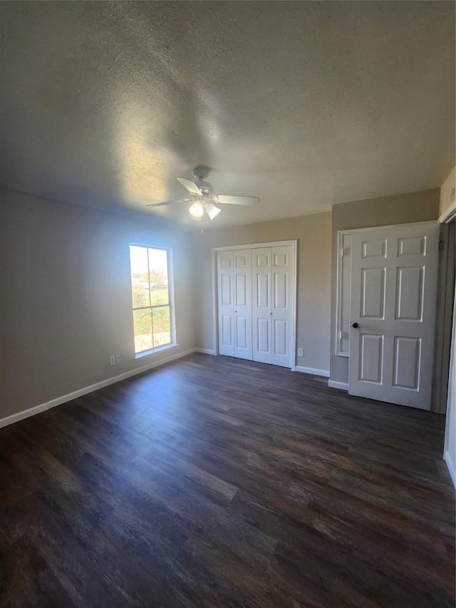 unfurnished bedroom with ceiling fan, a textured ceiling, dark hardwood / wood-style flooring, and a closet