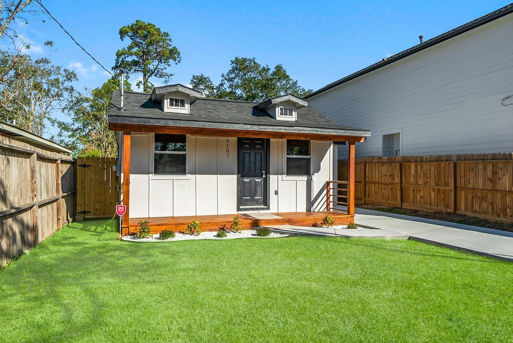 rear view of property featuring a porch and a yard