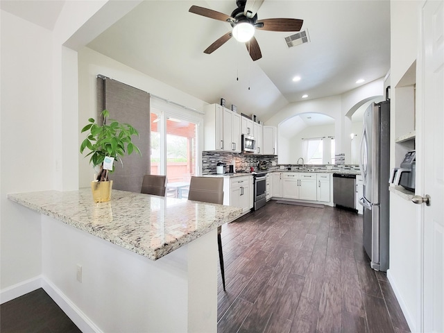 kitchen featuring stainless steel appliances, a kitchen bar, light stone countertops, and kitchen peninsula