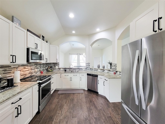 kitchen with stainless steel appliances, white cabinetry, backsplash, and light stone counters