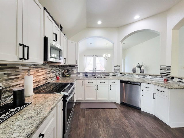 kitchen with kitchen peninsula, appliances with stainless steel finishes, white cabinetry, and decorative light fixtures