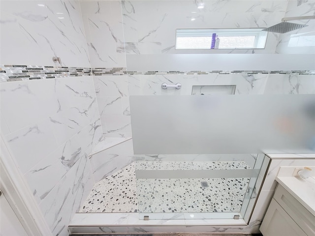 bathroom with a tile shower and vanity