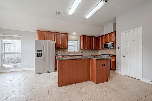 kitchen featuring lofted ceiling, sink, appliances with stainless steel finishes, a center island, and tasteful backsplash