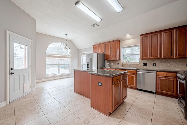 kitchen featuring sink, a center island, vaulted ceiling, appliances with stainless steel finishes, and dark stone counters