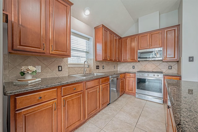 kitchen with sink, light tile patterned floors, dark stone countertops, stainless steel appliances, and backsplash