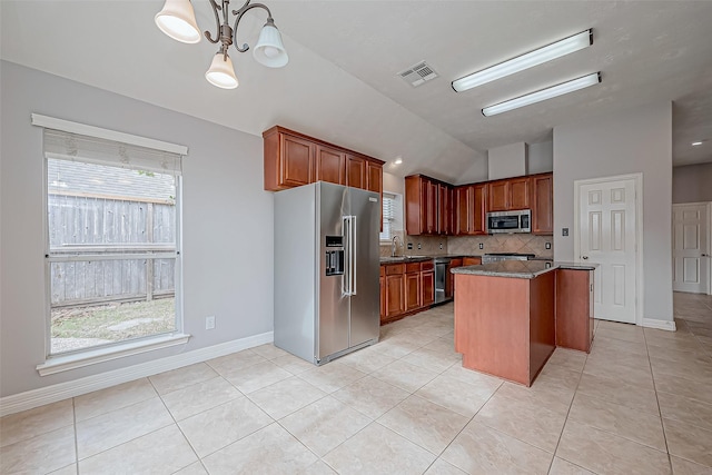 kitchen with a kitchen island, appliances with stainless steel finishes, tasteful backsplash, sink, and hanging light fixtures