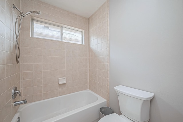 bathroom featuring tiled shower / bath combo and toilet