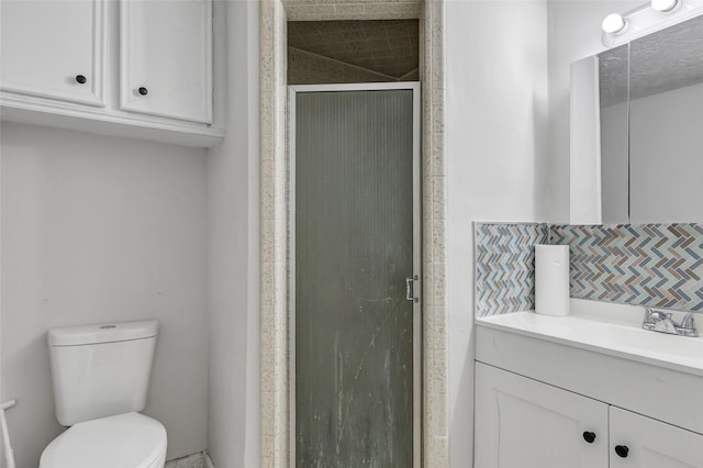 bathroom with an enclosed shower, vanity, decorative backsplash, and toilet