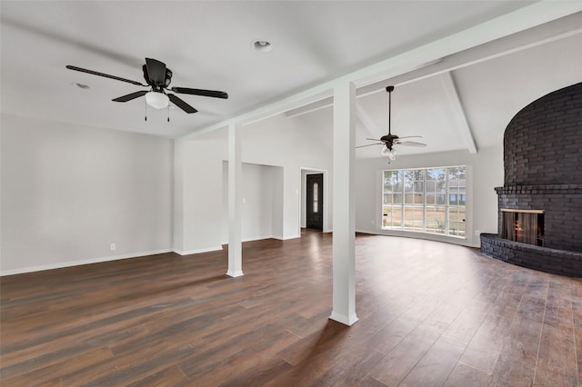 unfurnished living room with dark wood-type flooring, ceiling fan, a fireplace, and lofted ceiling with beams