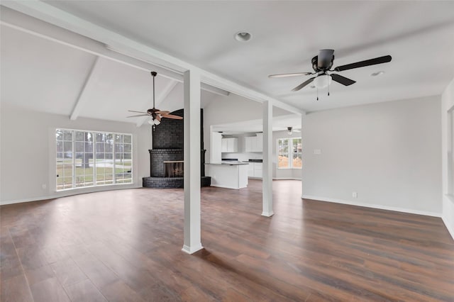 unfurnished living room featuring a fireplace, lofted ceiling with beams, dark hardwood / wood-style floors, and ceiling fan