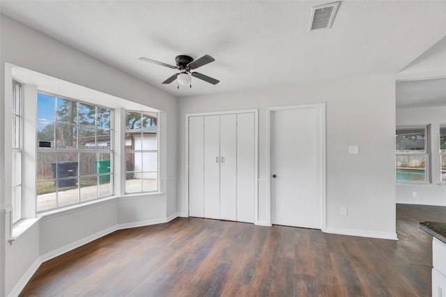 unfurnished bedroom with multiple windows, dark hardwood / wood-style floors, and ceiling fan