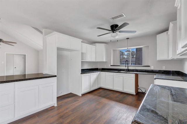 kitchen with dark wood-type flooring, sink, hanging light fixtures, dark stone countertops, and white cabinets