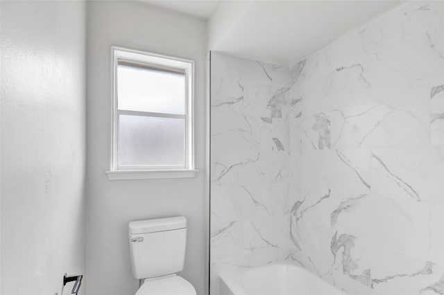 bathroom featuring toilet and tiled shower / bath