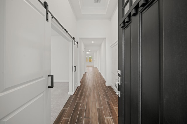 corridor featuring a raised ceiling and a barn door