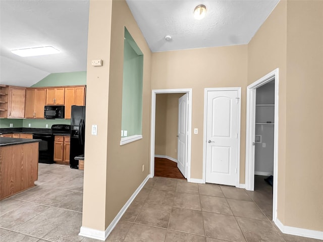 kitchen with lofted ceiling, light tile patterned floors, and black appliances