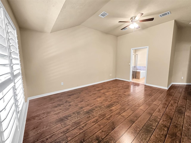 empty room with lofted ceiling, dark hardwood / wood-style floors, a textured ceiling, and ceiling fan