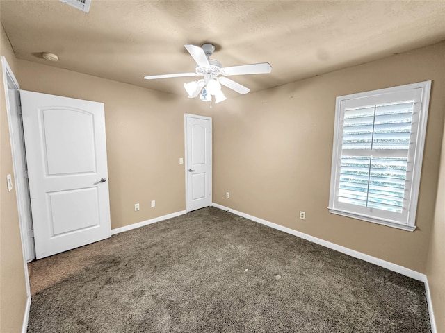 unfurnished bedroom with ceiling fan, a textured ceiling, and dark carpet