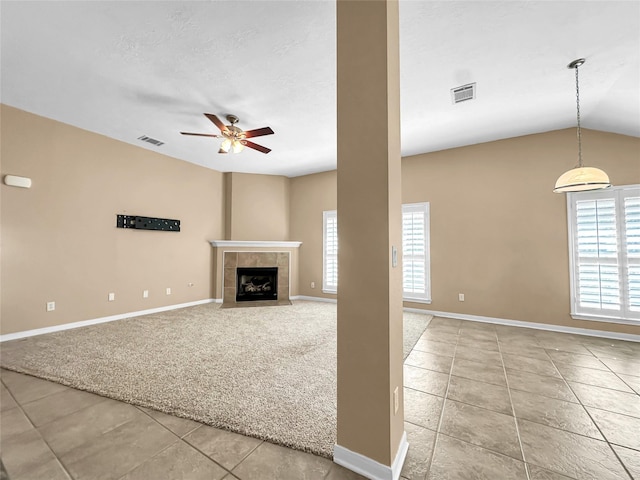 unfurnished living room with lofted ceiling, light carpet, a textured ceiling, ceiling fan, and a tiled fireplace