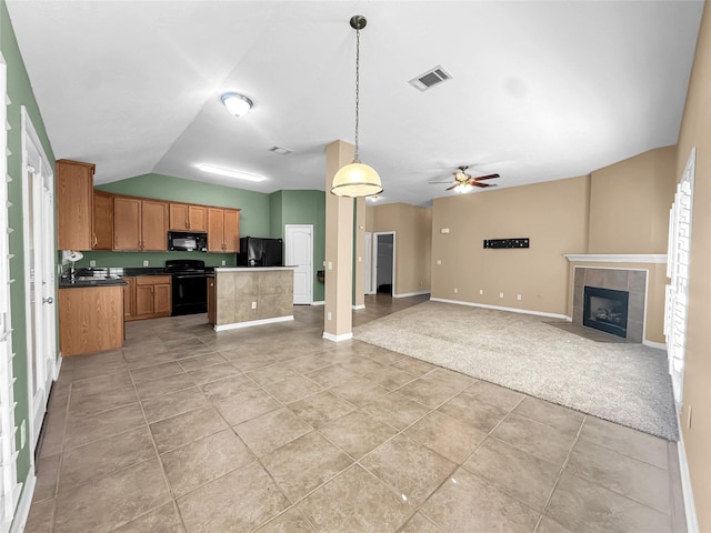 kitchen featuring vaulted ceiling, a fireplace, hanging light fixtures, a center island, and black appliances