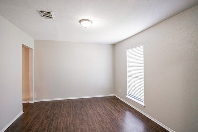 empty room featuring dark wood-type flooring and a textured ceiling