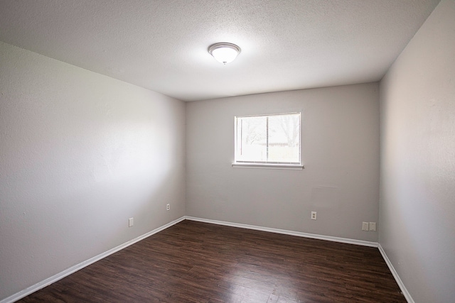 empty room with dark wood-type flooring and a textured ceiling