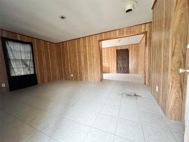 empty room featuring wooden walls and light tile patterned flooring