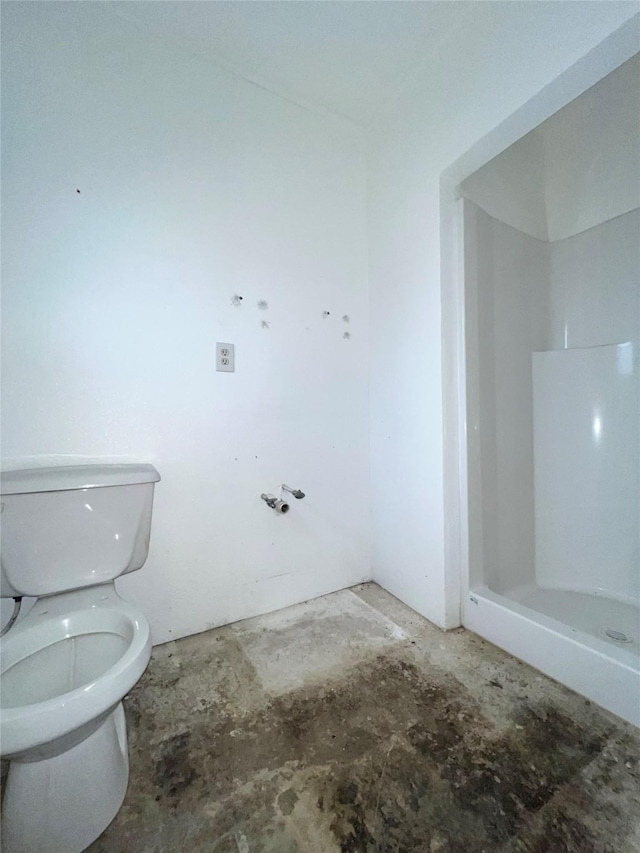 bathroom with toilet, concrete flooring, and a shower