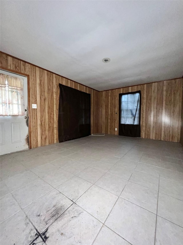 unfurnished living room featuring light tile patterned floors and wood walls