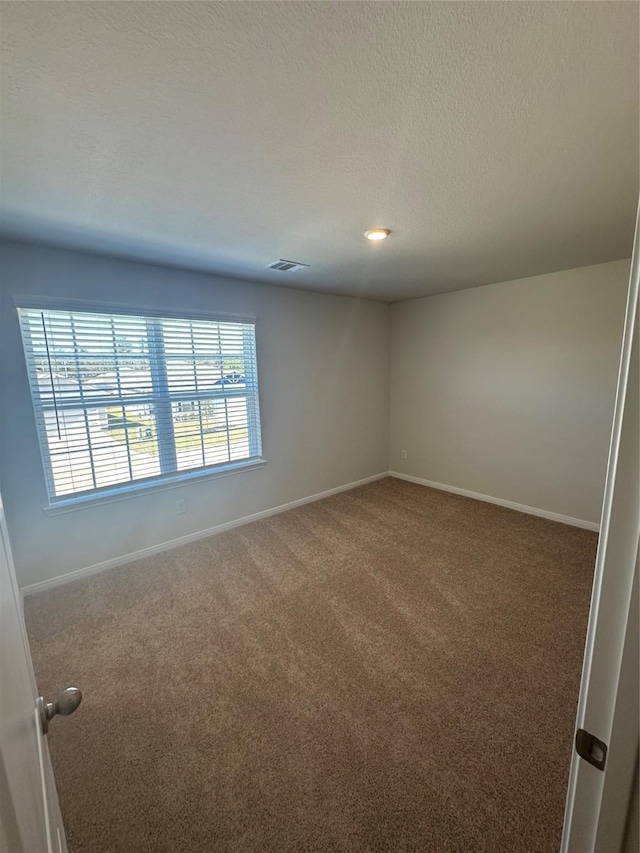 unfurnished room featuring a textured ceiling and dark colored carpet