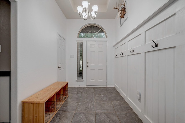 foyer with baseboards, a high ceiling, and a notable chandelier