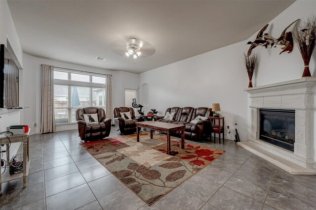 living room with light tile patterned floors, ceiling fan, a glass covered fireplace, and visible vents