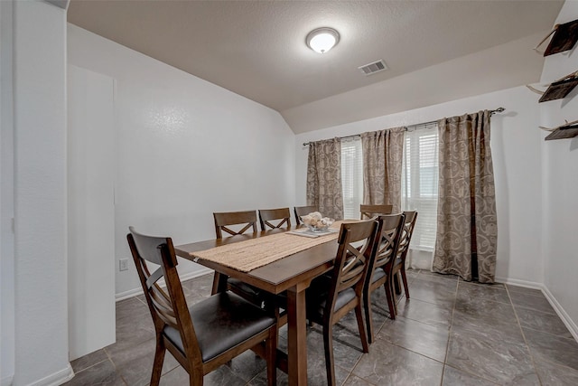 dining room featuring lofted ceiling, visible vents, a textured ceiling, and baseboards