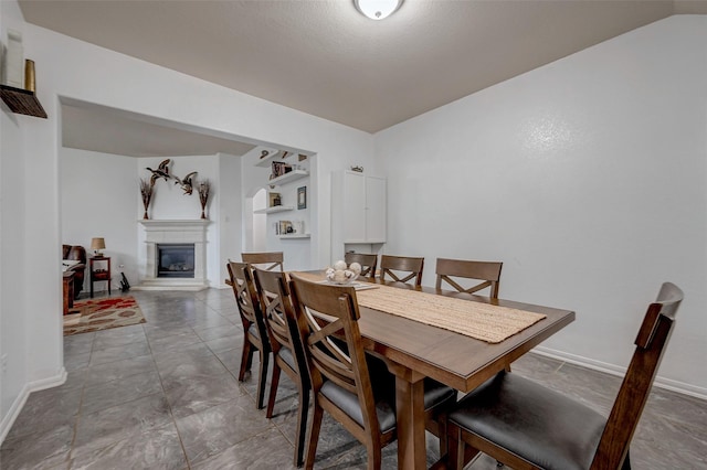 dining area featuring a glass covered fireplace and baseboards