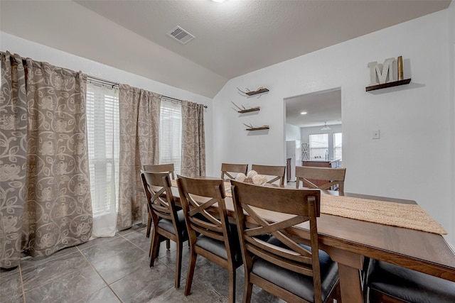 dining area featuring tile patterned flooring, visible vents, and vaulted ceiling