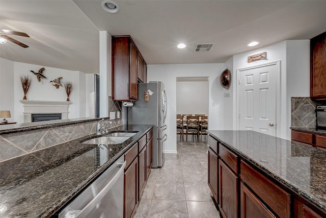 kitchen featuring stainless steel appliances, dark stone countertops, a sink, and visible vents