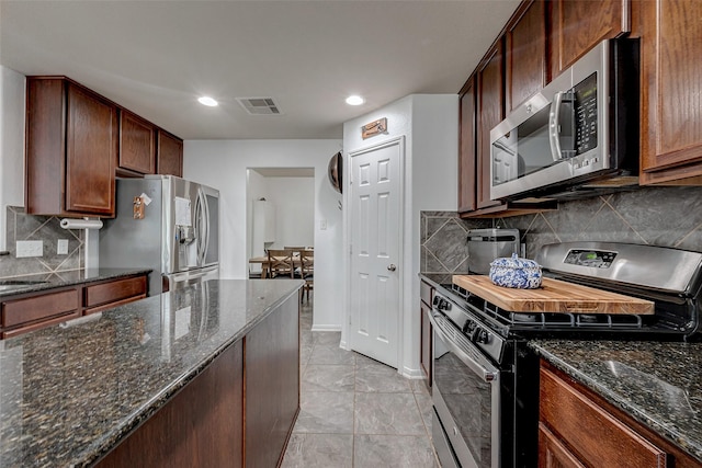 kitchen with stainless steel appliances, dark stone counters, visible vents, and tasteful backsplash