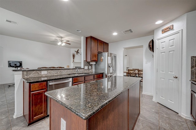 kitchen featuring dark stone counters, stainless steel appliances, visible vents, and a center island