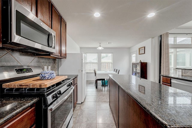 kitchen with light tile patterned floors, tasteful backsplash, visible vents, dark stone countertops, and stainless steel appliances