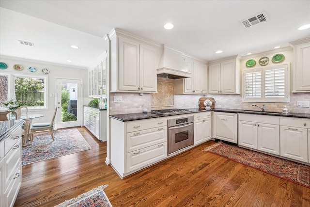 kitchen with dark countertops, custom range hood, visible vents, and stainless steel appliances