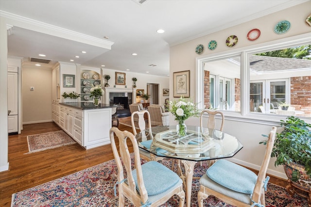 dining area with a wealth of natural light, visible vents, a fireplace, and wood finished floors