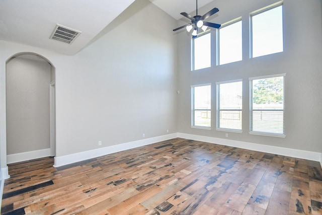 spare room with a towering ceiling, hardwood / wood-style floors, and ceiling fan