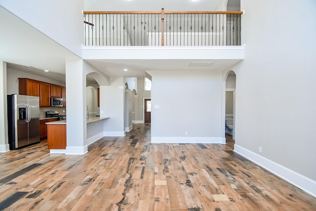 unfurnished living room with a high ceiling and light hardwood / wood-style flooring