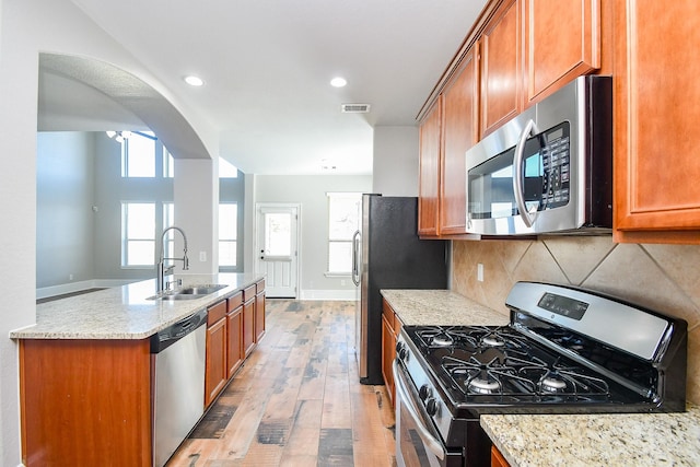 kitchen with stainless steel appliances, light stone countertops, sink, and backsplash