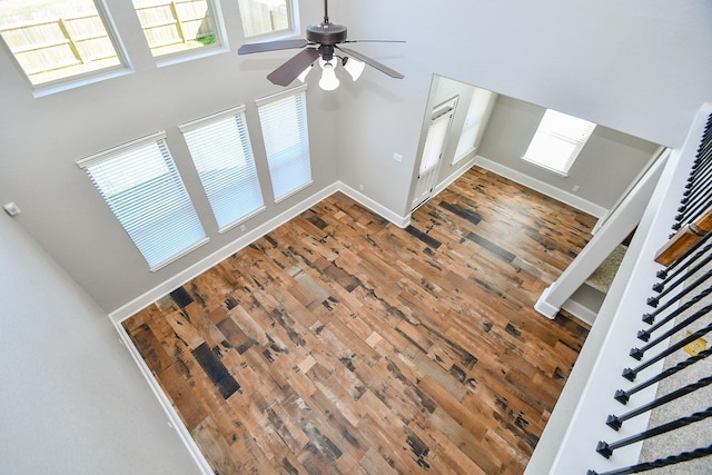 living room featuring ceiling fan, hardwood / wood-style floors, and a towering ceiling