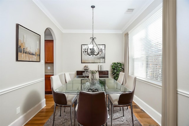 dining area with crown molding, a notable chandelier, and hardwood / wood-style flooring