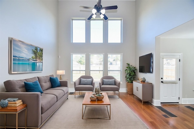 living room with a towering ceiling, plenty of natural light, and light wood-type flooring