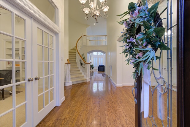 entrance foyer featuring baseboards, wood finished floors, stairs, french doors, and a notable chandelier