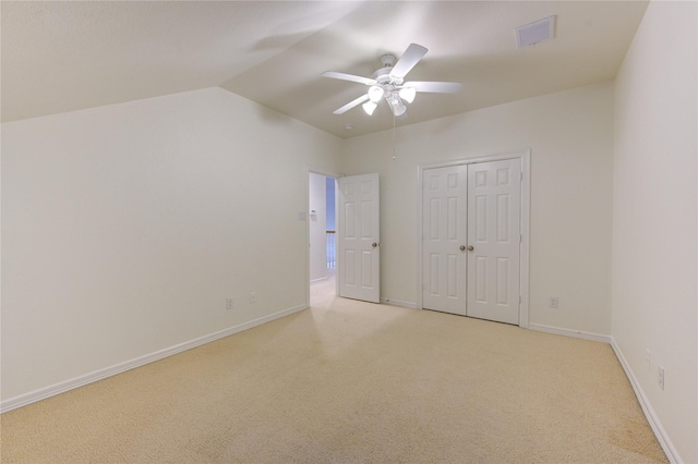 unfurnished bedroom featuring light carpet, visible vents, baseboards, vaulted ceiling, and a closet