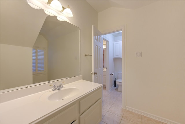 bathroom with lofted ceiling, toilet, vanity, baseboards, and tile patterned floors